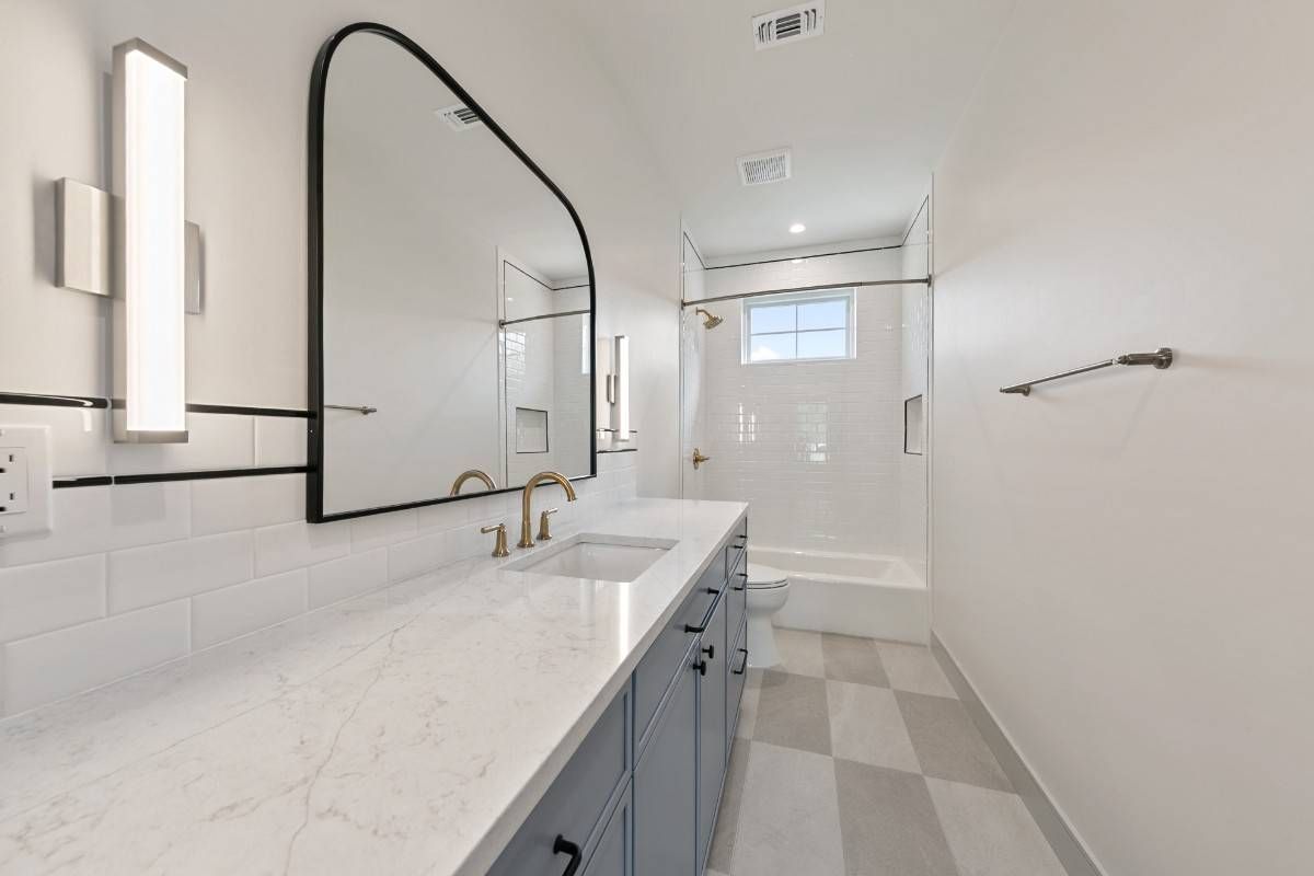 Bathroom with blue vanity, large arched mirror, and checkered floor.