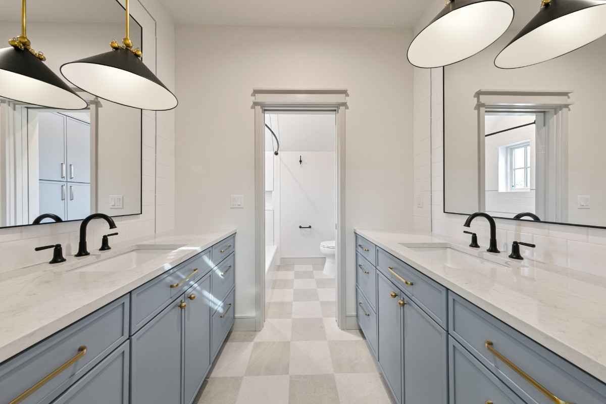 A modern bathroom with two vanities, blue cabinets, and black fixtures.