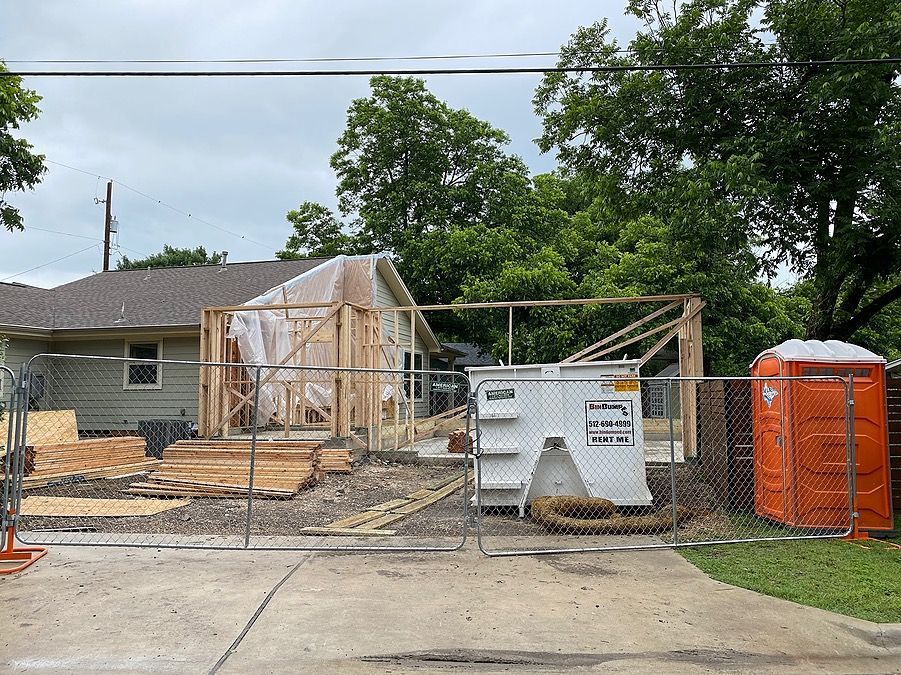 A house is being remodeled and a dumpster is in front of it.