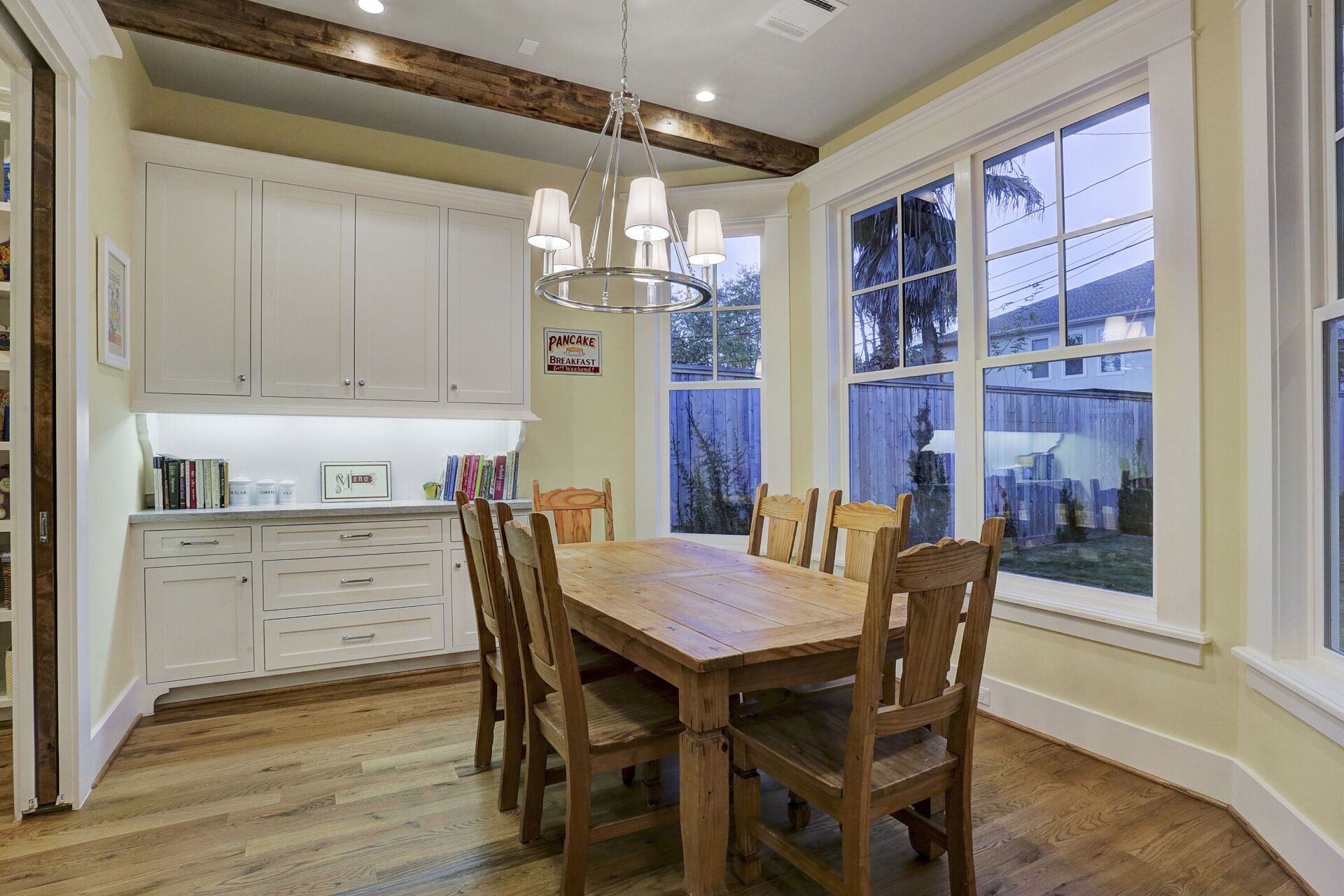 A dining room with a wooden table and chairs and a chandelier.