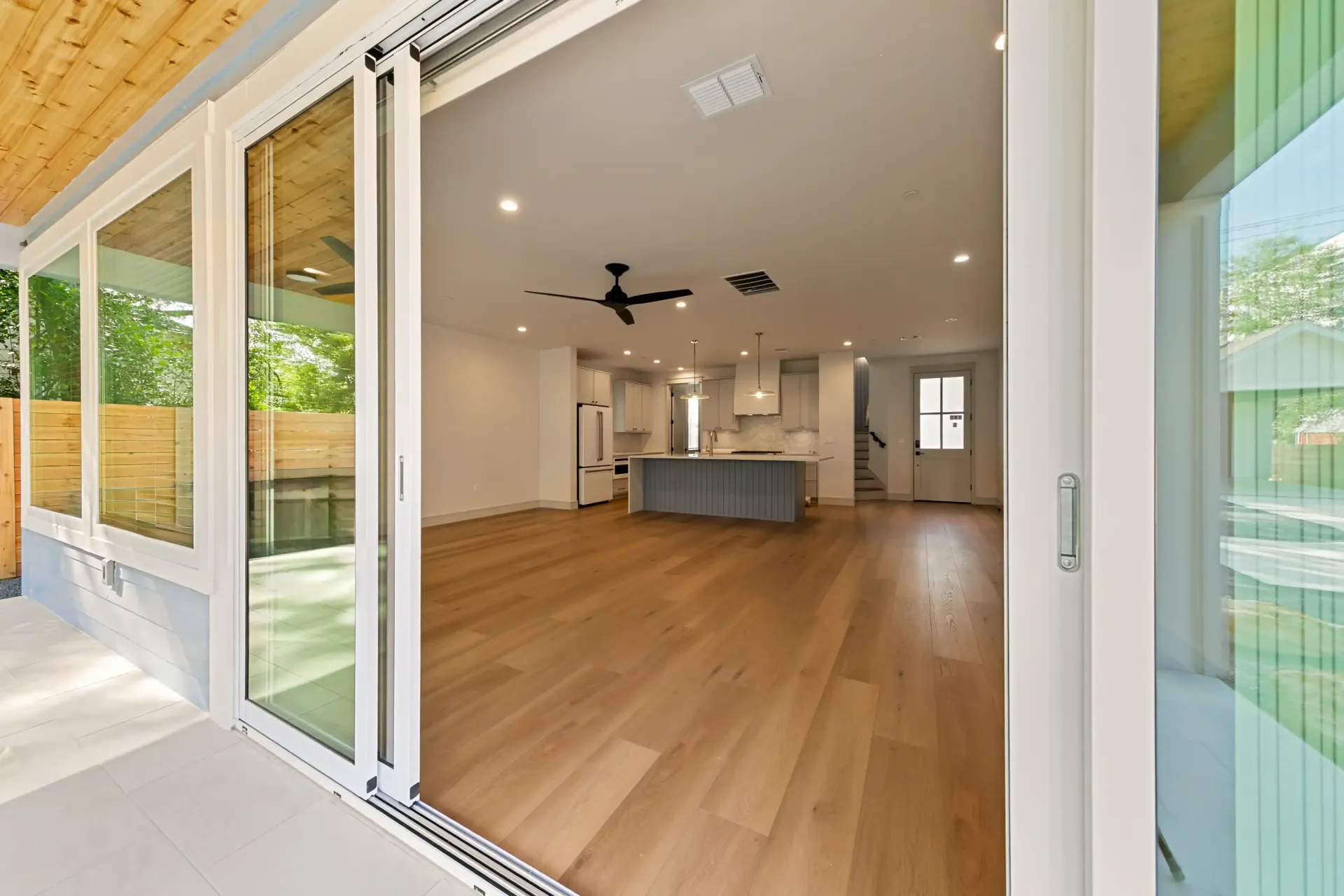 Open living room with sliding glass doors, hardwood floors, and gray kitchen island.