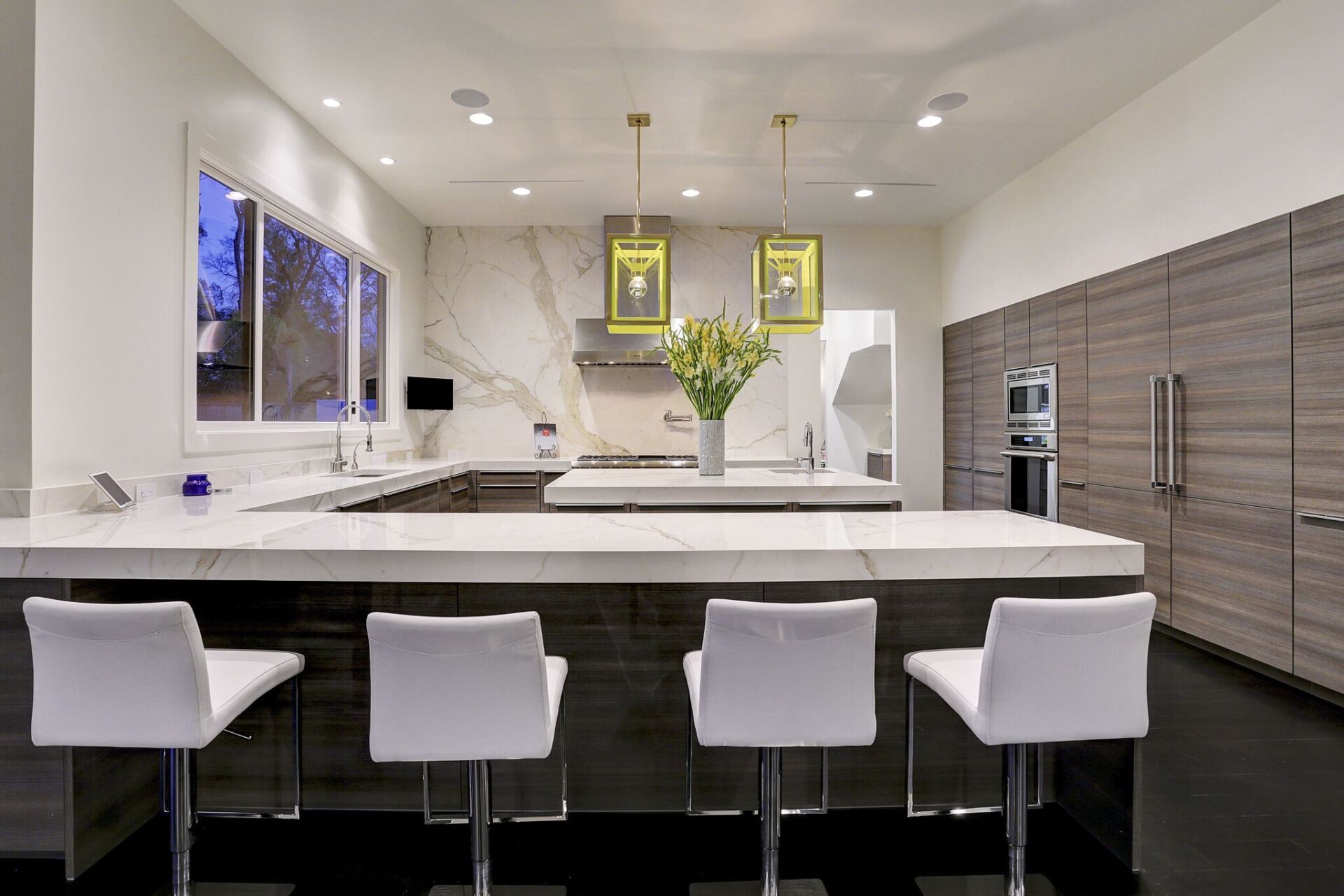 A kitchen with a large island and four white chairs.