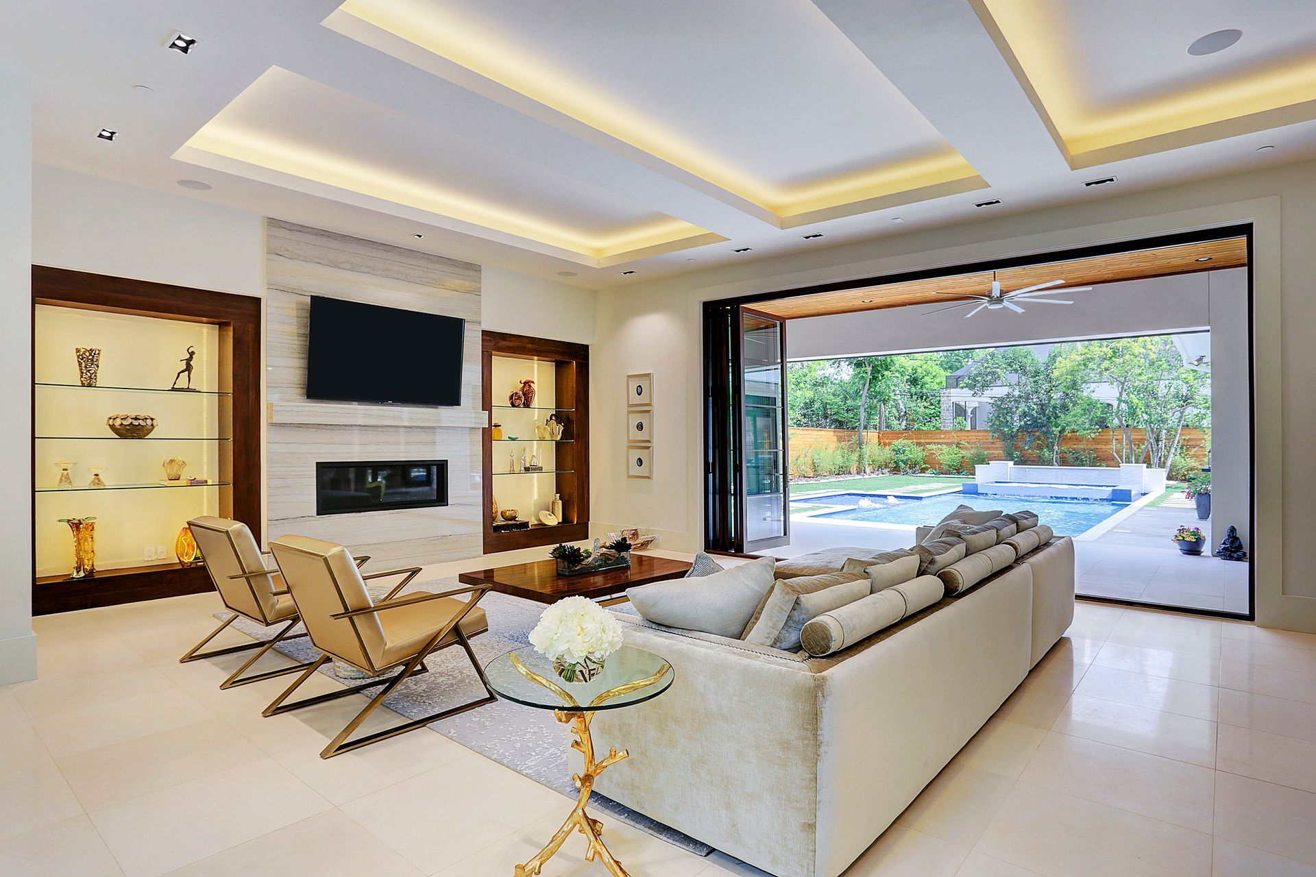 Living room with a fireplace, display cases, and open doors to a pool.