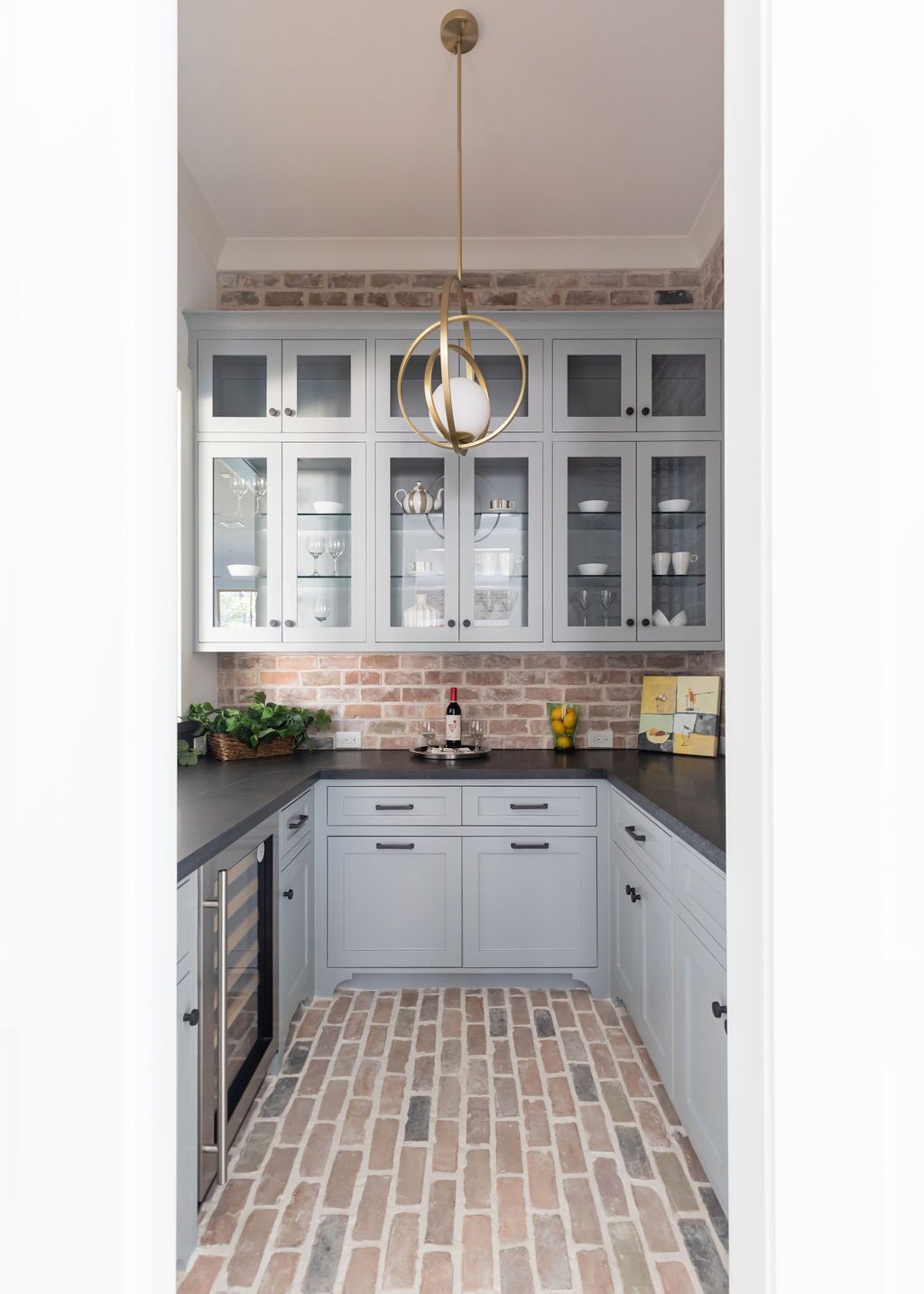 A kitchen with white cabinets and a brick floor.