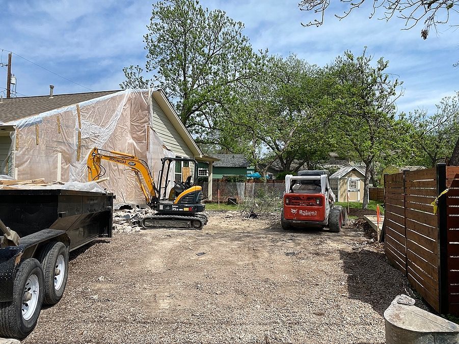 A house is being demolished and a bulldozer is parked in front of it.