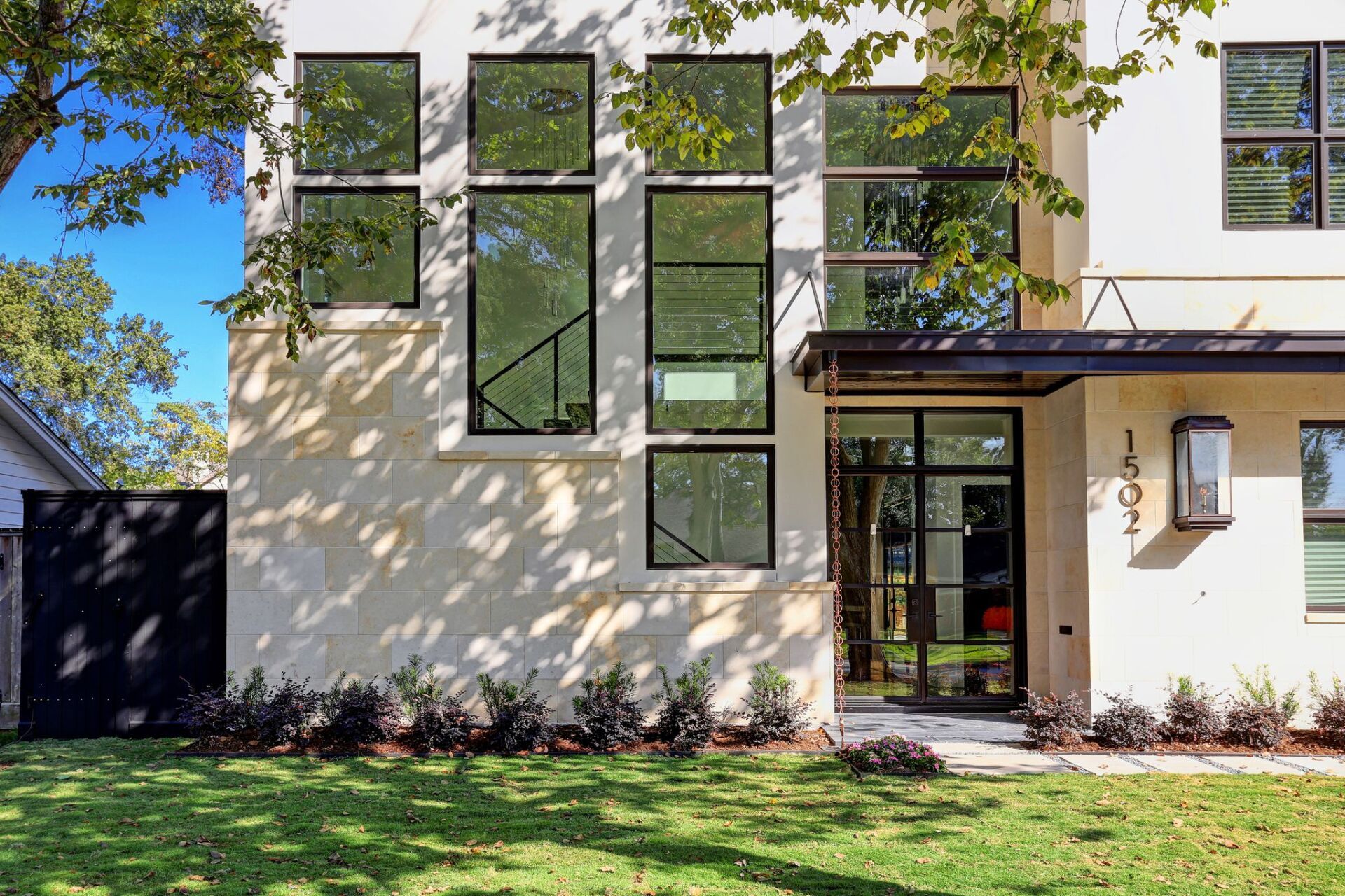 A white house with a lot of windows is sitting on top of a lush green lawn.