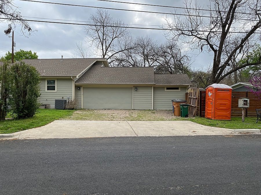 A house with a garage and a portable toilet in front of it.