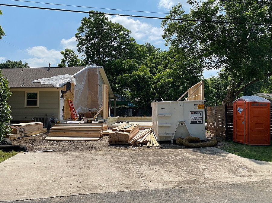 A house under construction with a dumpster in front of it.
