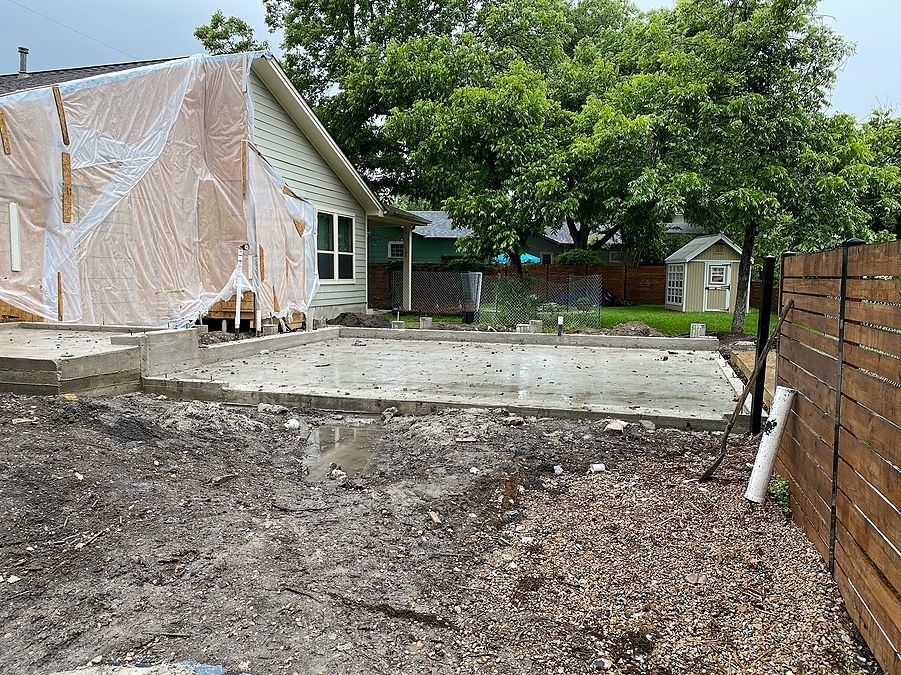 A house is being built in a backyard with a wooden fence.