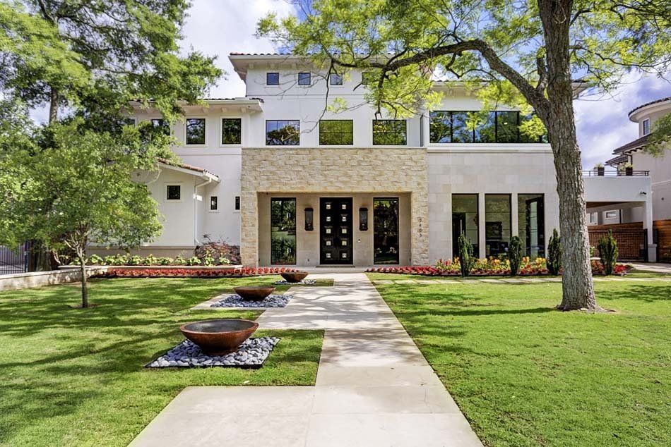 A large white house with a lush green lawn and trees in front of it.