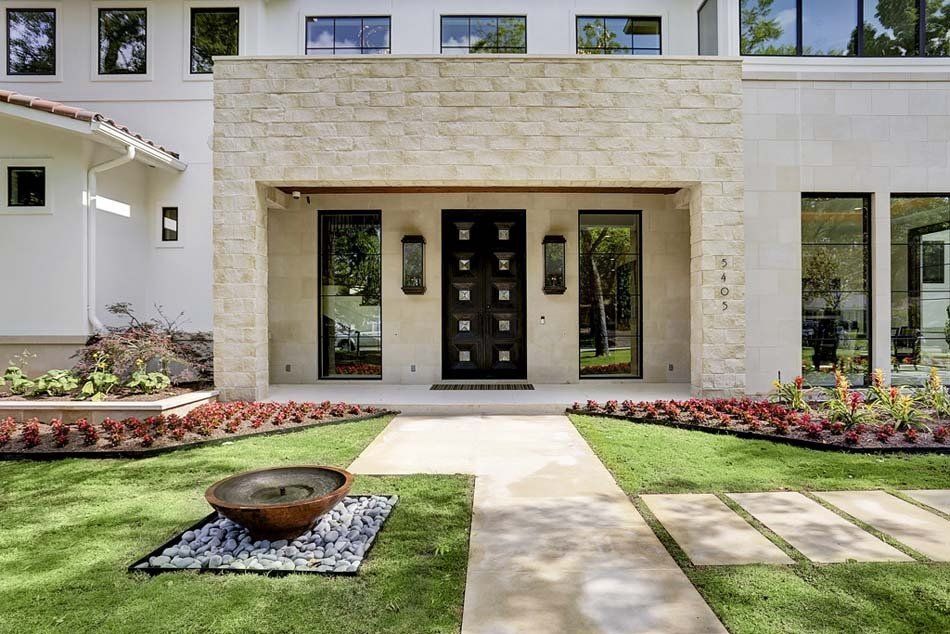 A large white house with a black door and a walkway leading to it.