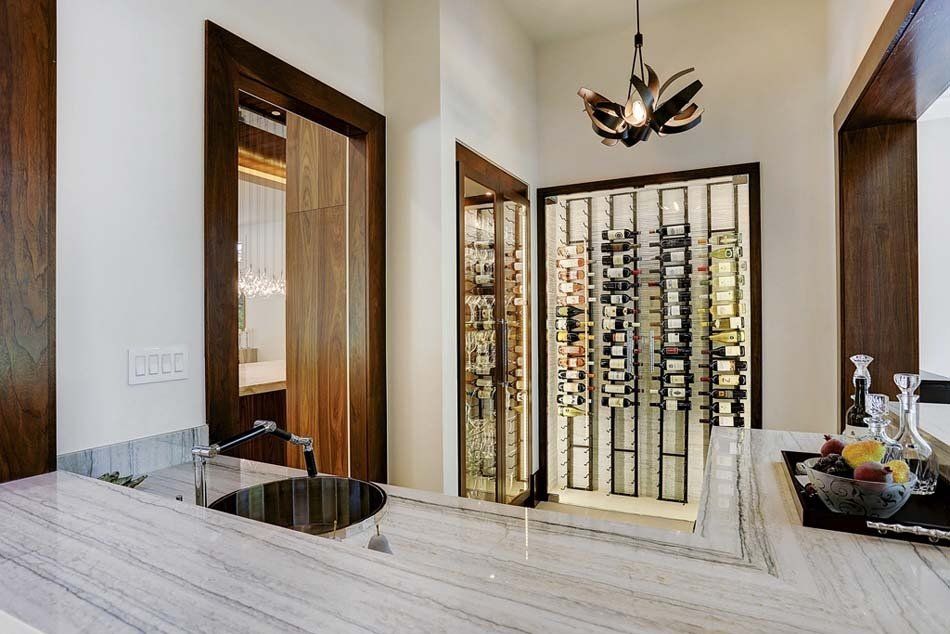 A kitchen with a sink and a wine cellar in the background.