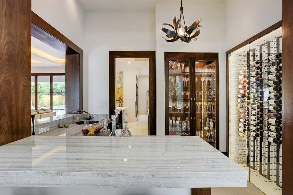 A kitchen with a marble counter top and a wine cellar.