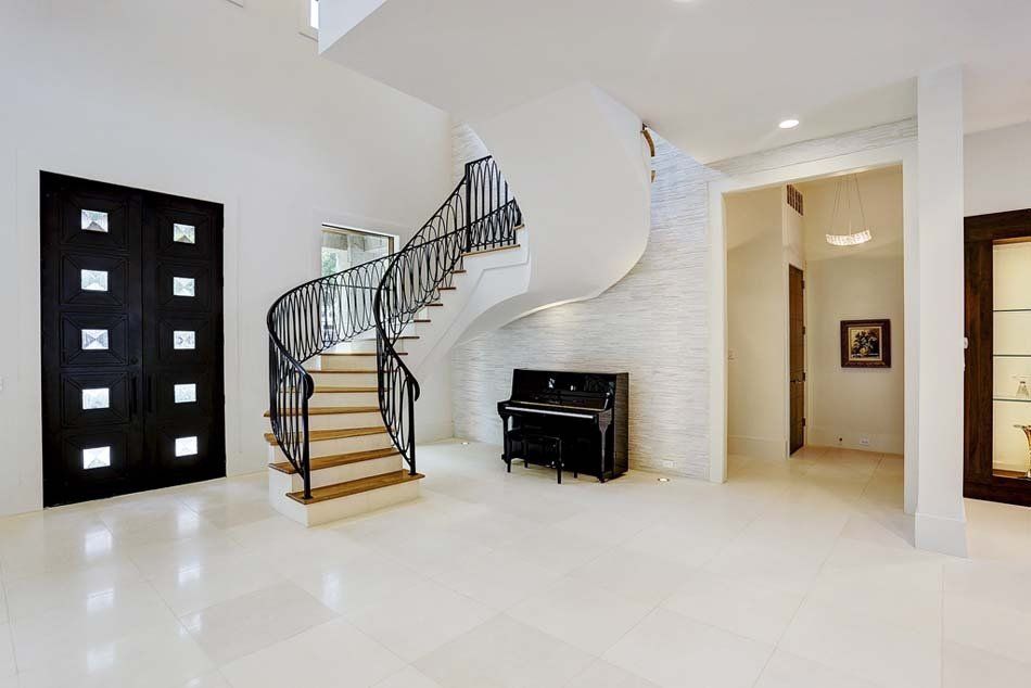 A large hallway with a spiral staircase and a piano.