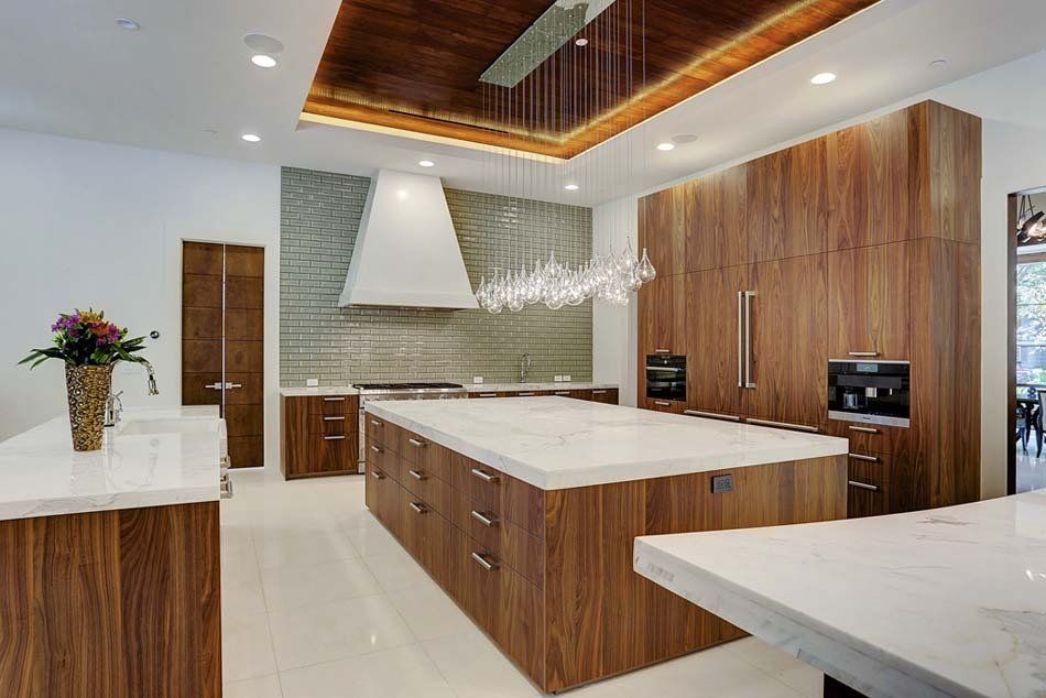 A kitchen with wooden cabinets , white counter tops , and a large island.