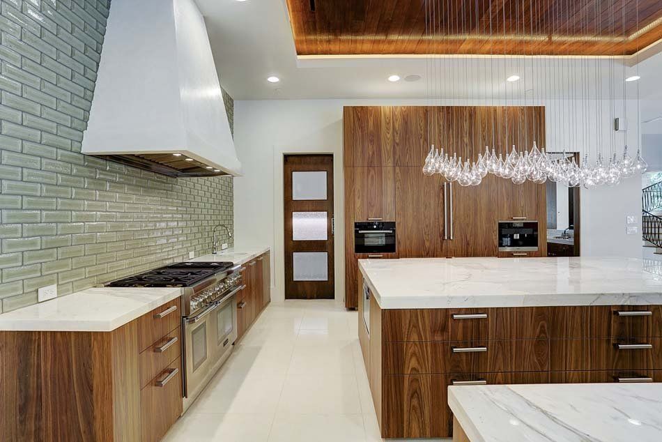A kitchen with wooden cabinets , white counter tops , stainless steel appliances and a large island.