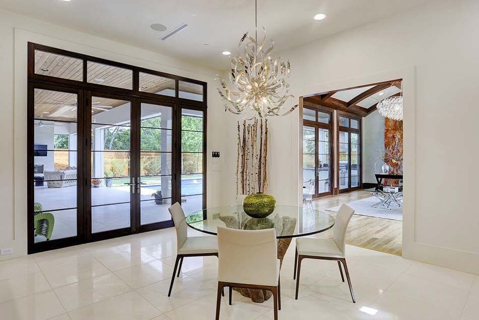 A dining room with a glass table and chairs and a chandelier.