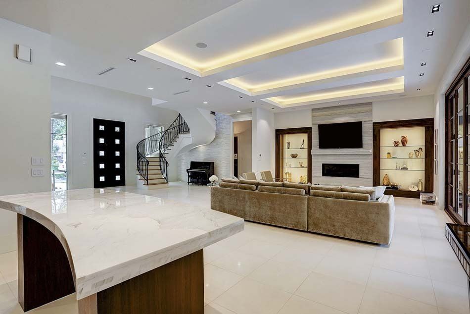 A large living room with a couch , television , fireplace and stairs.