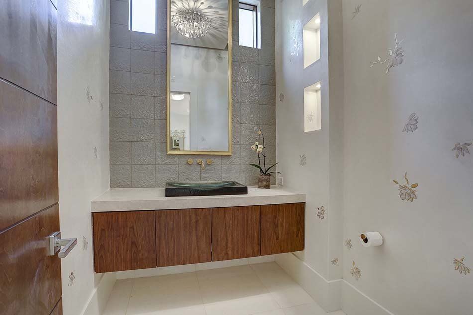 A bathroom with a sink , mirror , and toilet paper.