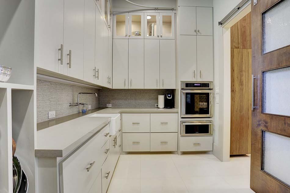 A kitchen with white cabinets , stainless steel appliances and a sliding barn door.