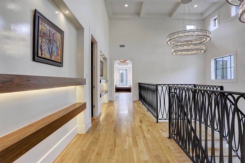 A hallway with hardwood floors and a staircase in a house.