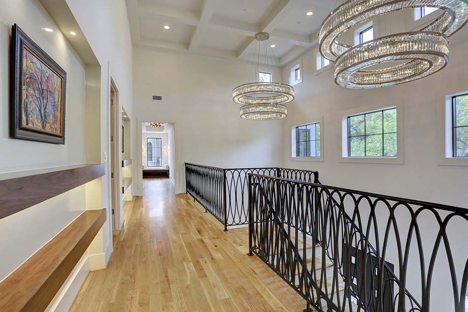 A long hallway with a railing and a chandelier hanging from the ceiling.