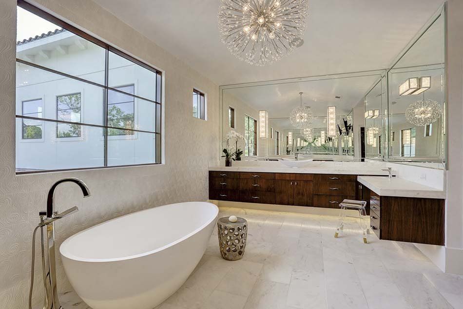 A bathroom with a bathtub , sinks , mirrors and a chandelier.