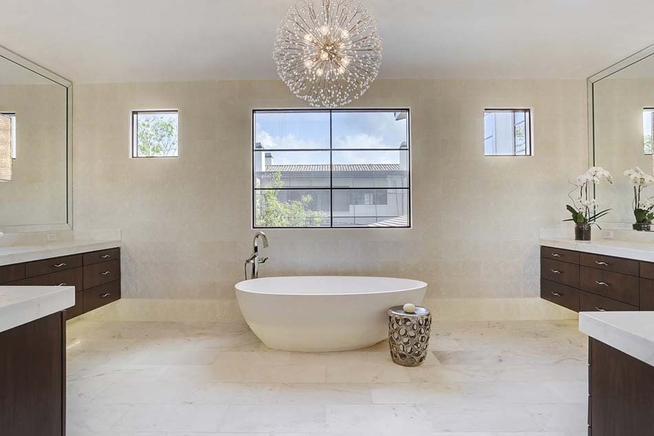 A bathroom with a bathtub , sinks , mirrors and a chandelier.