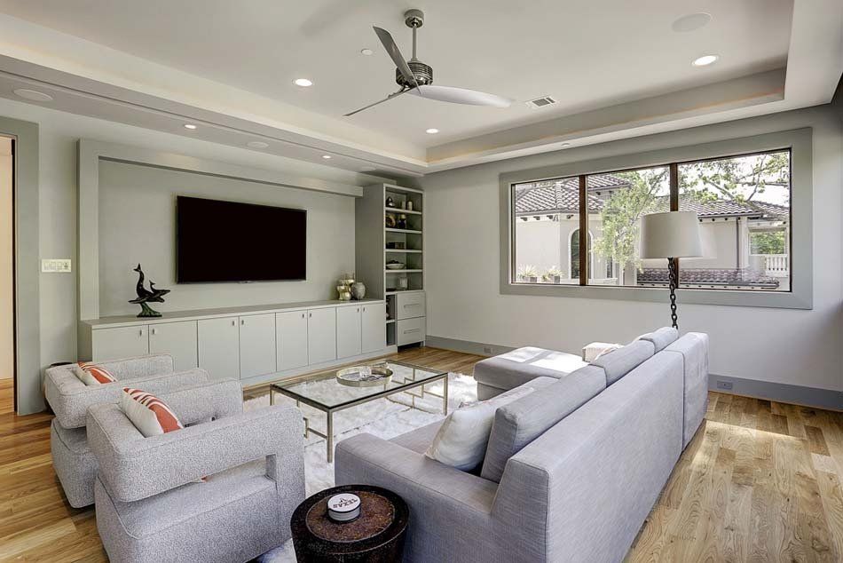A living room with a couch , chairs , a television and a ceiling fan.