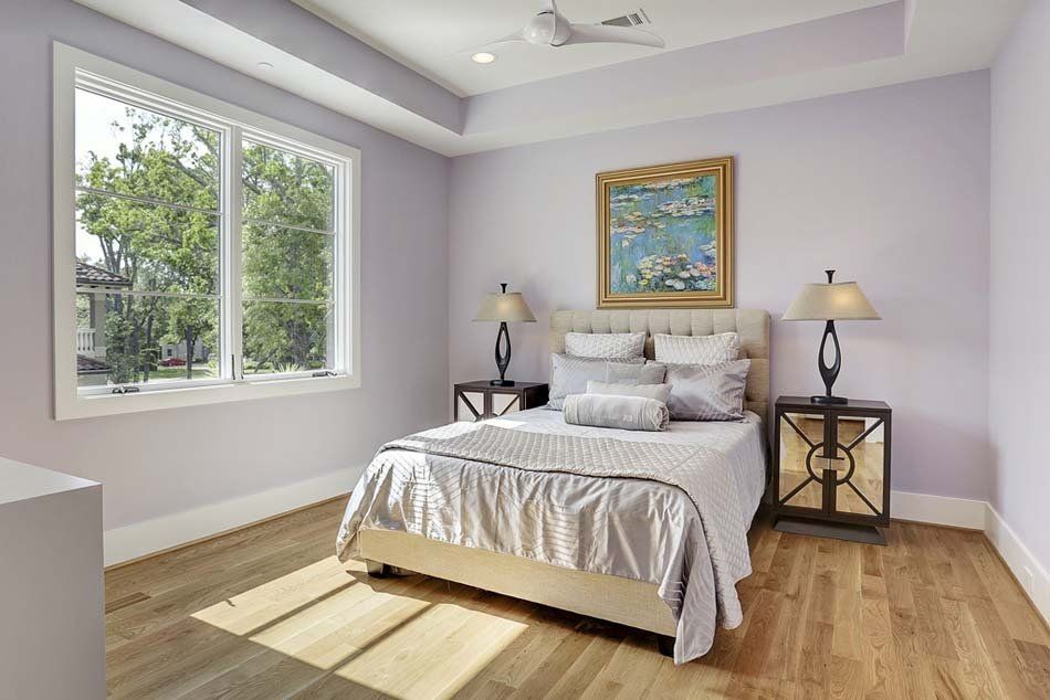 A bedroom with a bed , lamps , and a painting on the wall.