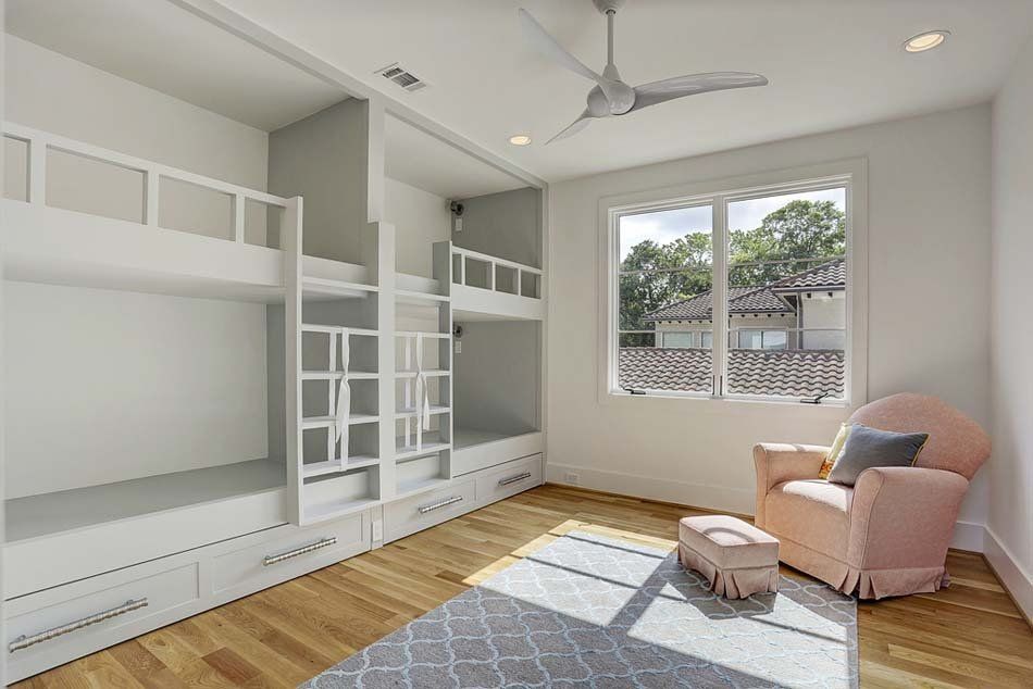 A bedroom with bunk beds , a chair and a ceiling fan.