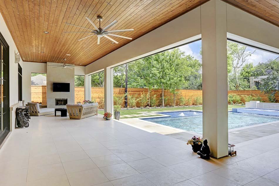 A large covered patio with a ceiling fan and a swimming pool.