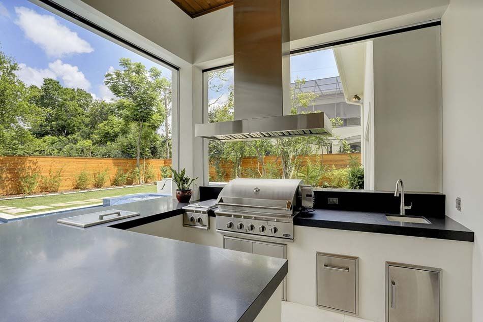A kitchen with a grill , sink , and large windows.