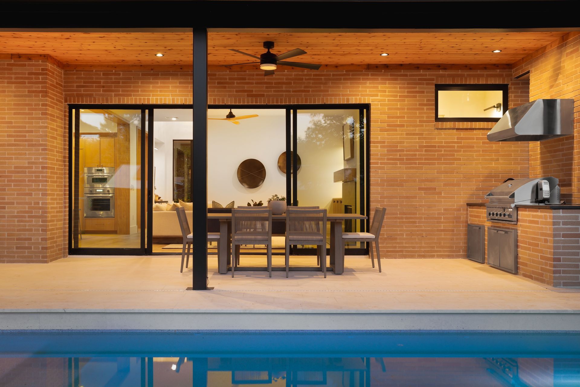 A patio with a table and chairs next to a swimming pool.