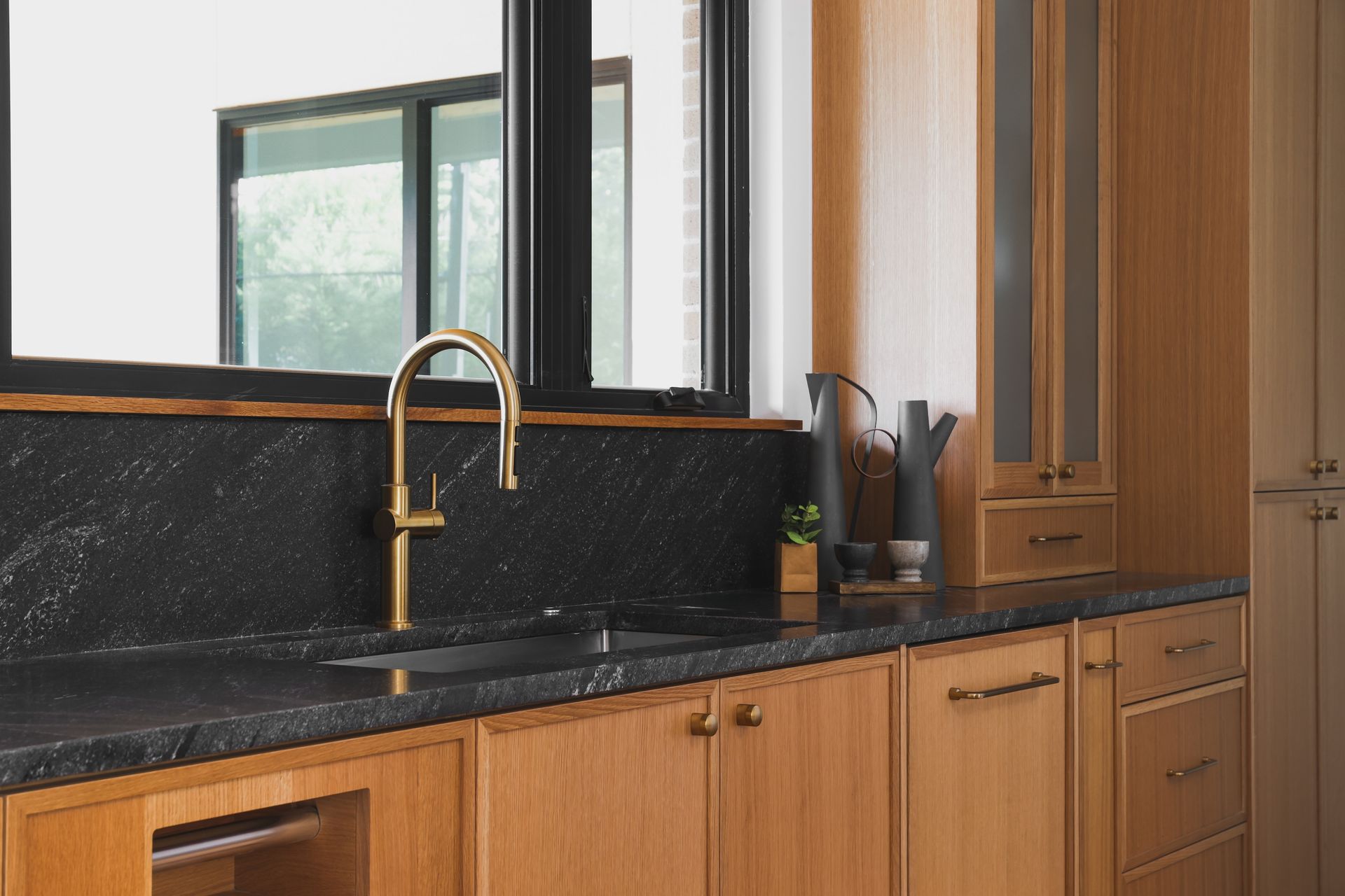 A kitchen with wooden cabinets , a sink , and a window.