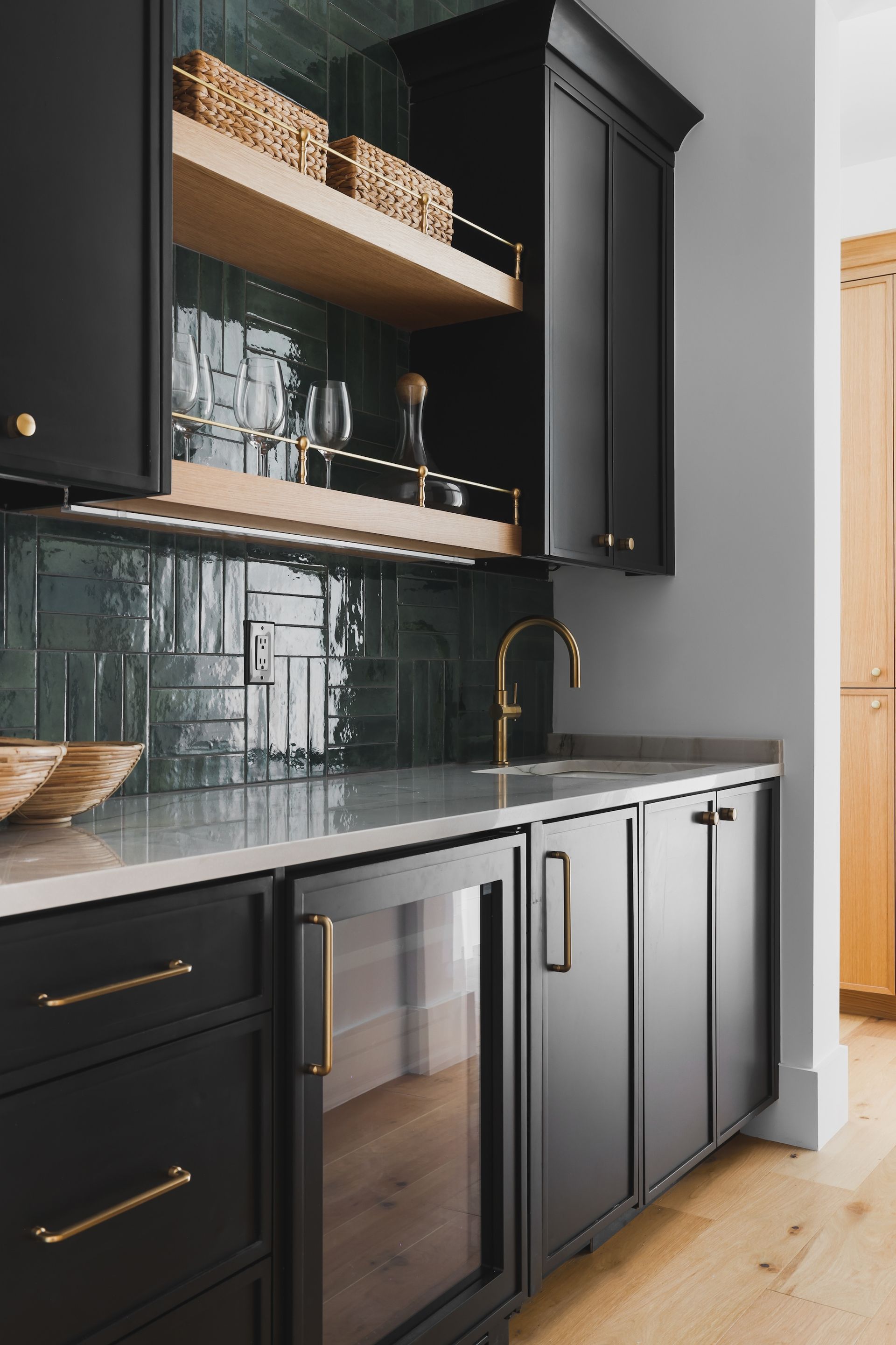 A kitchen with black cabinets and a glass door refrigerator.