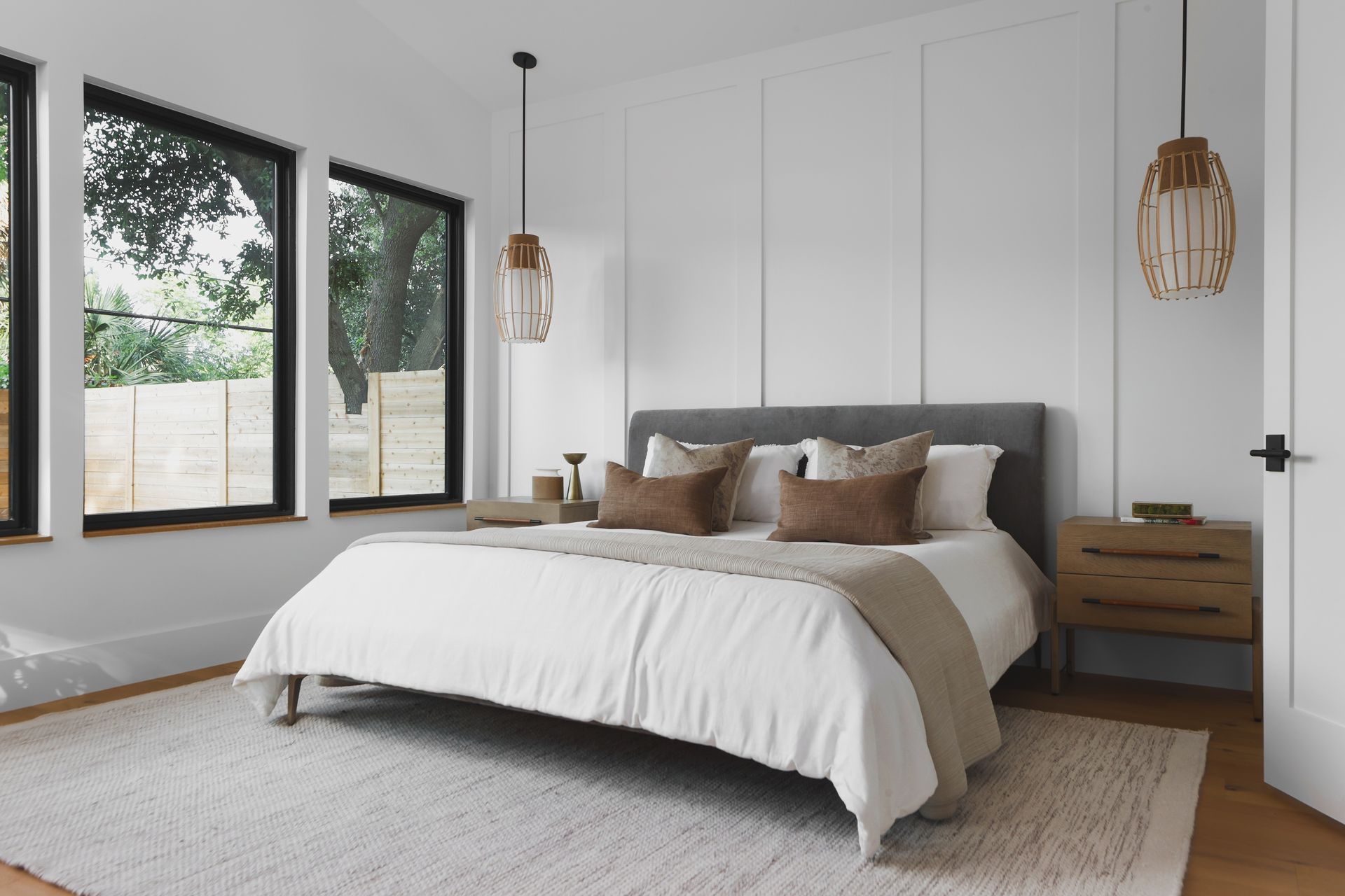 A bedroom with a bed , nightstand , and two windows.