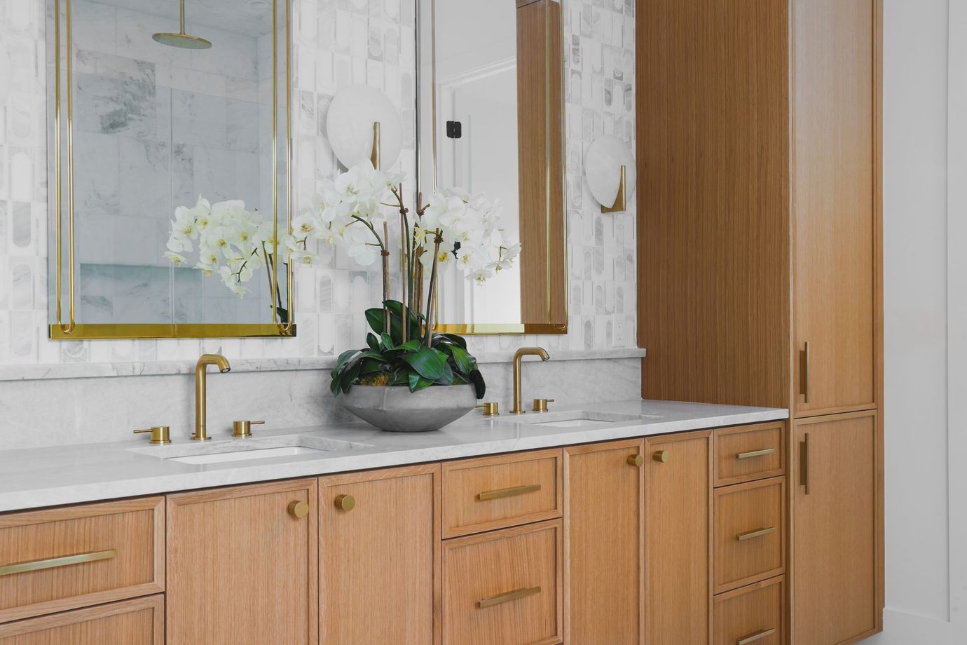 A bathroom with two sinks , a mirror , and wooden cabinets.