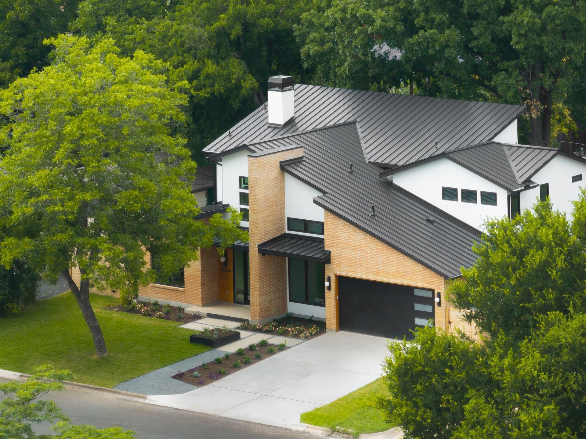 An aerial view of a large house with a black roof