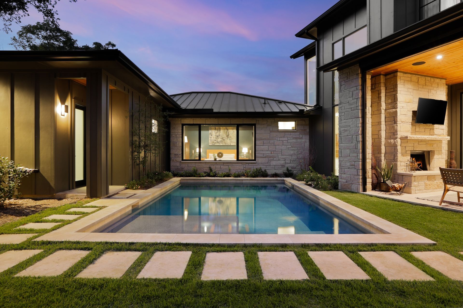 A large swimming pool is in the backyard of a house.