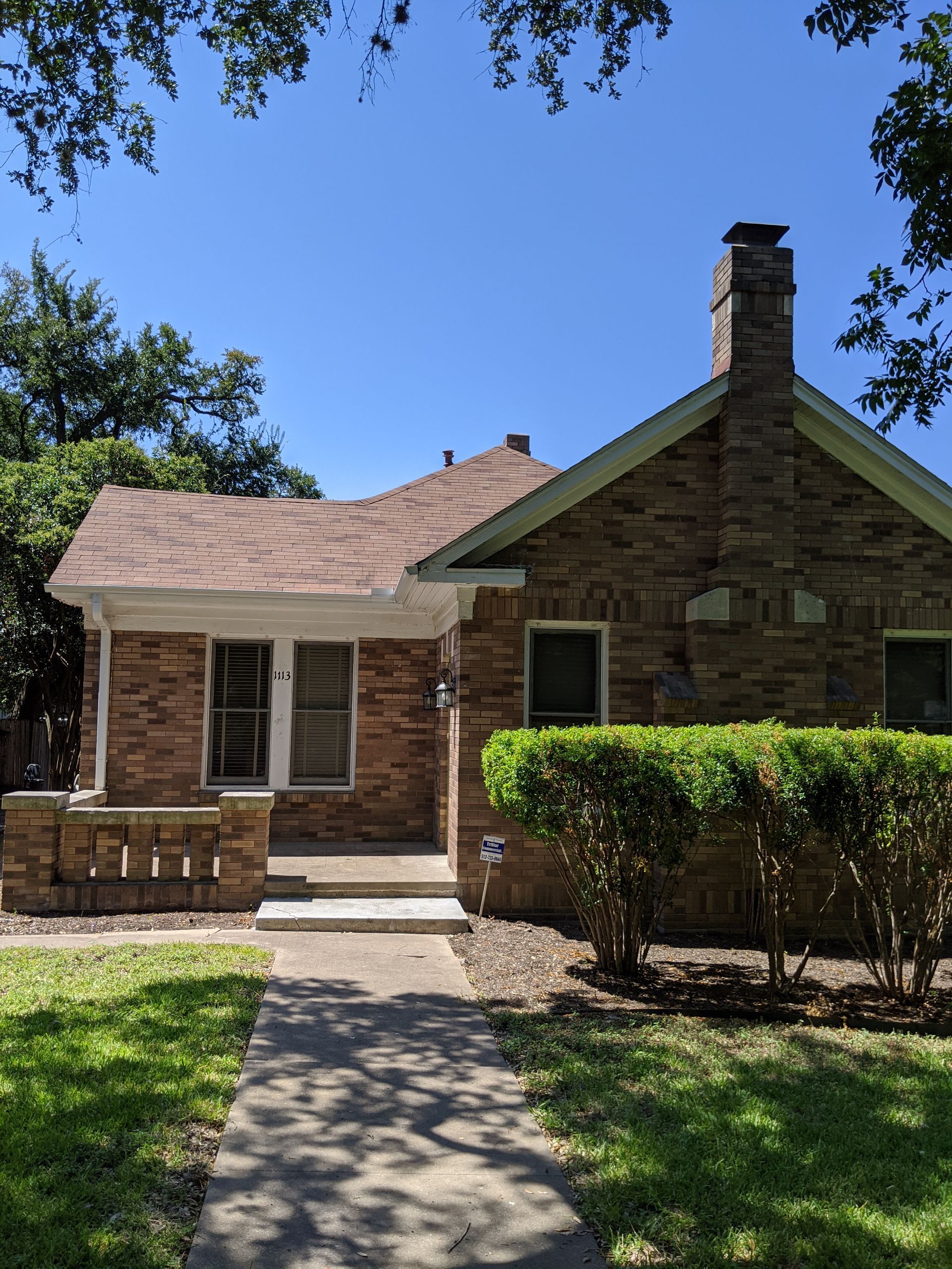 A brick house with a chimney and a walkway leading to it