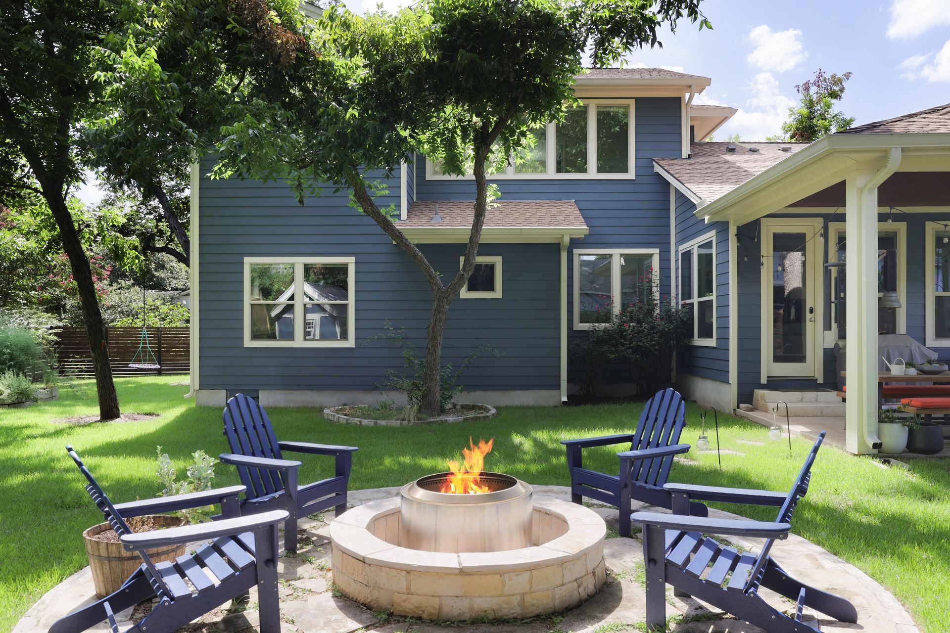 A fire pit with chairs around it in front of a house.
