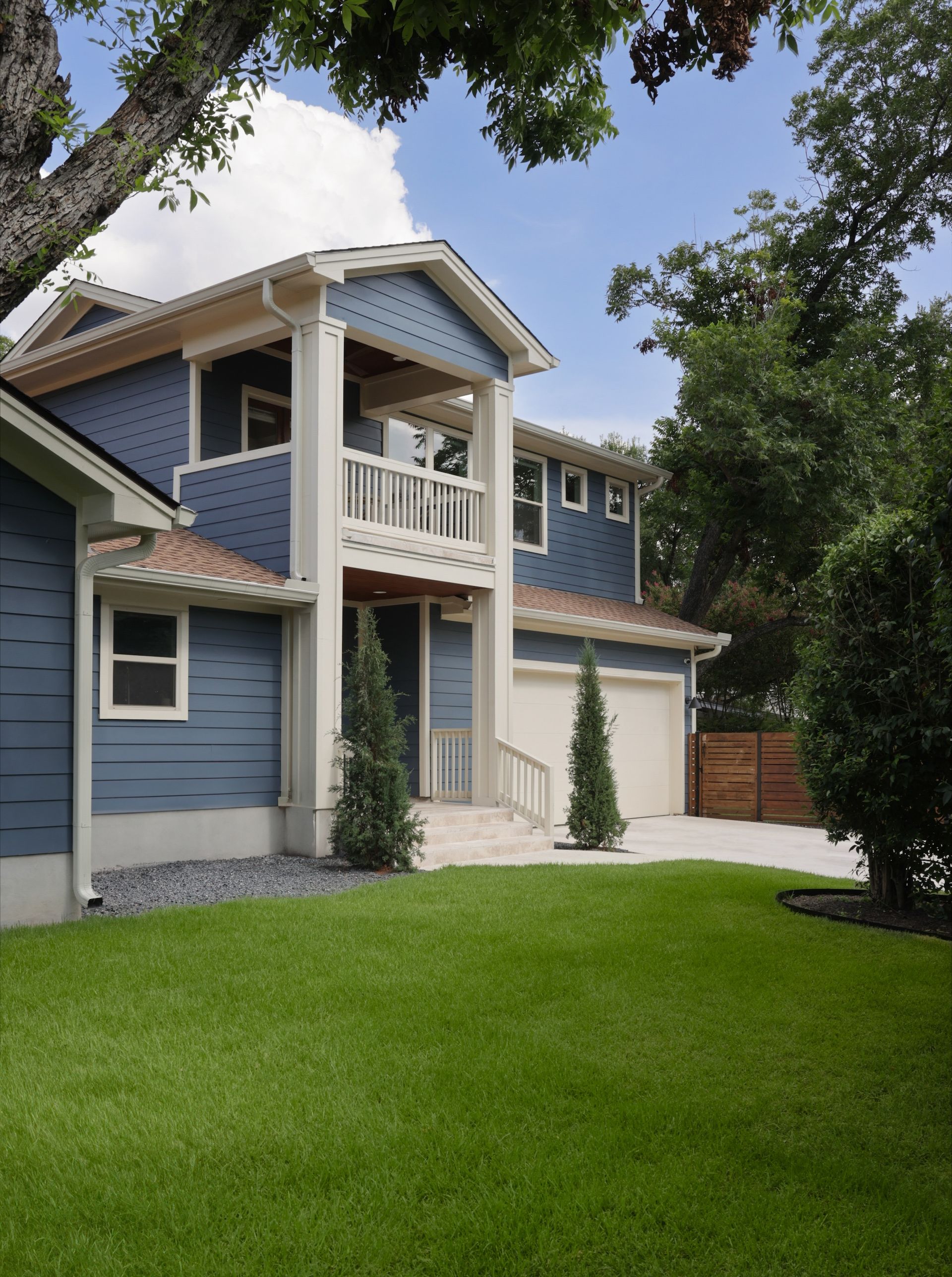 A blue and white house with a lush green lawn in front of it