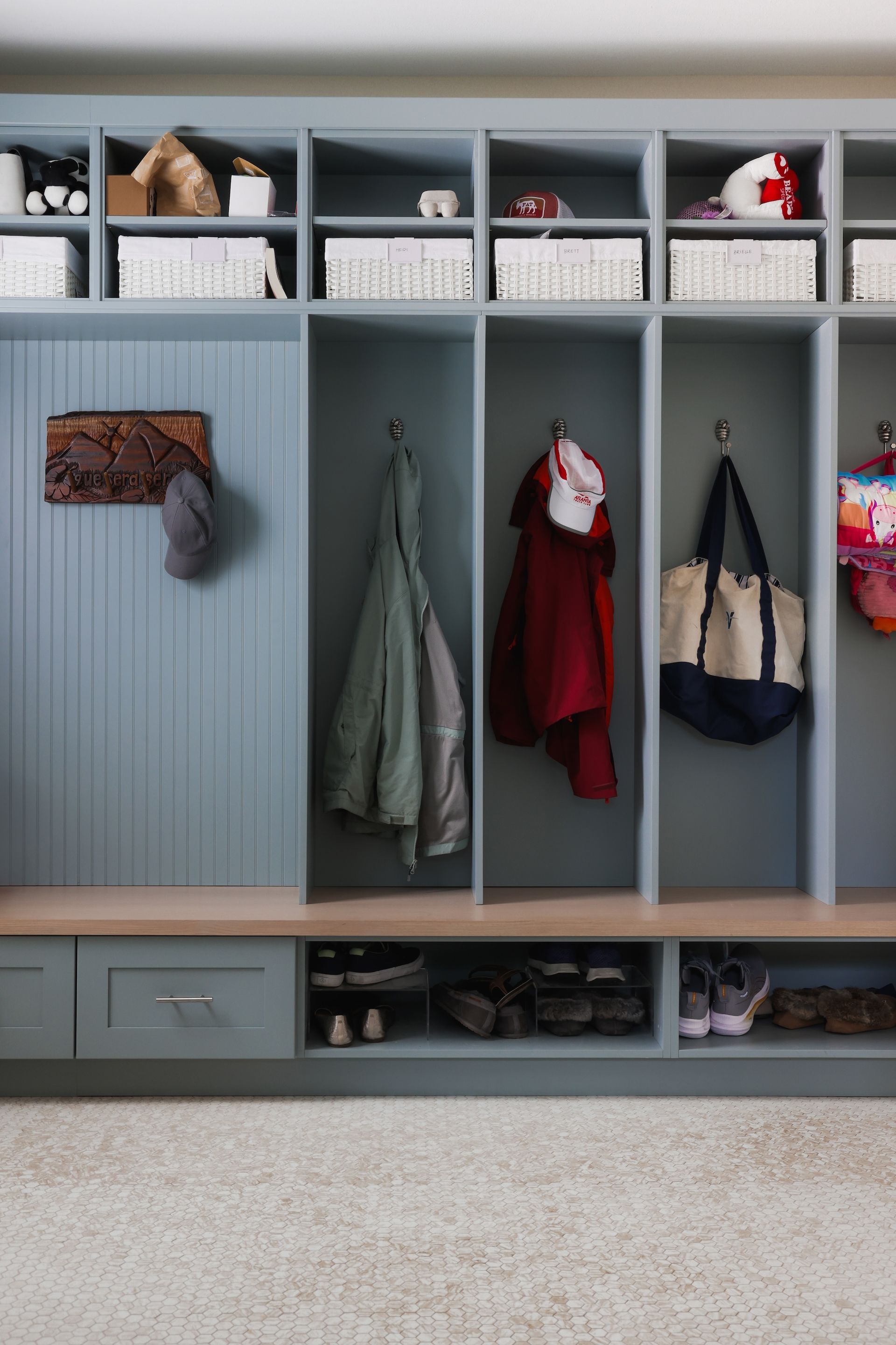 A closet with clothes hanging on the wall and baskets on the shelves