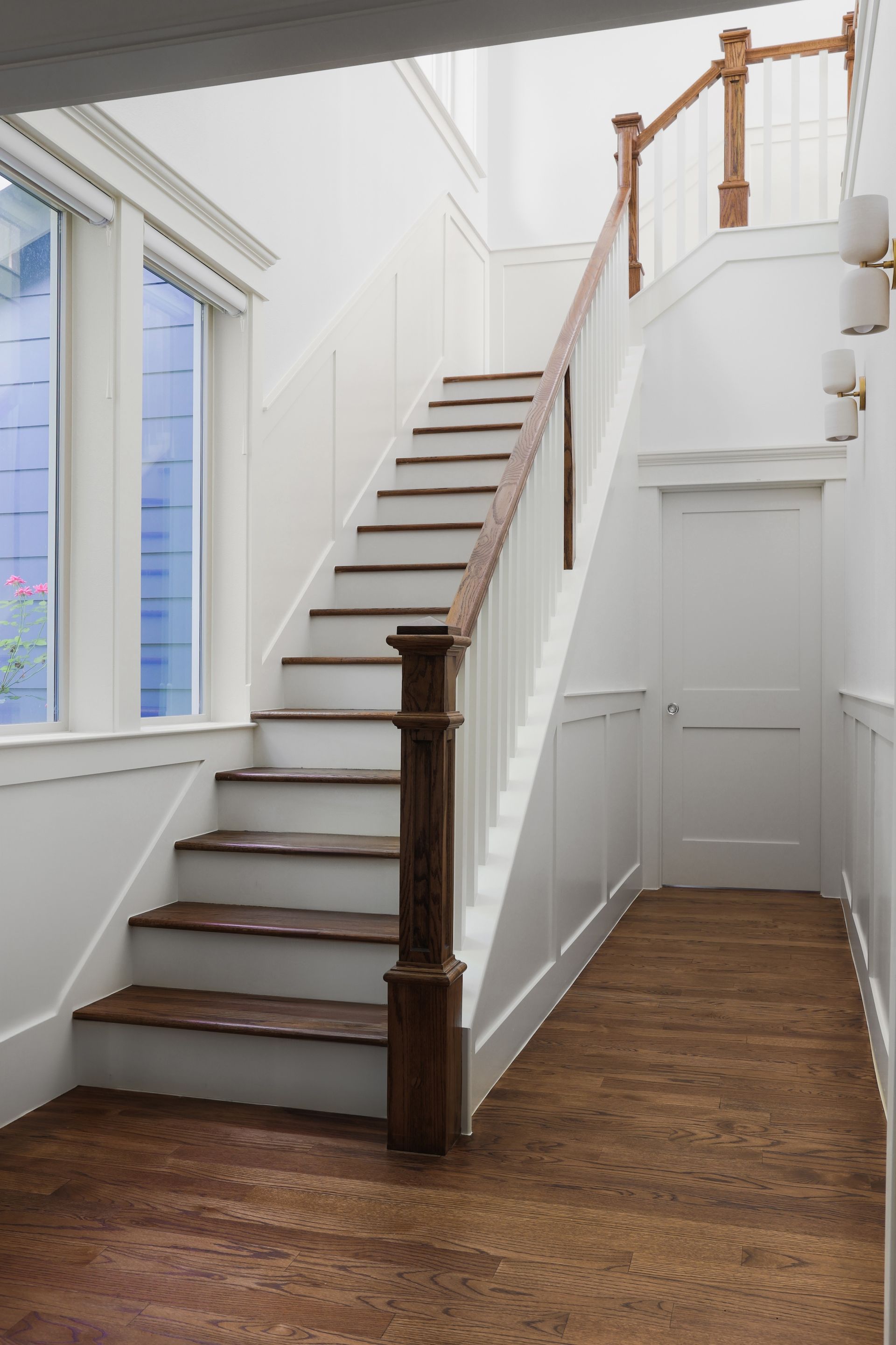 A white staircase with wooden steps and a wooden railing in a hallway.