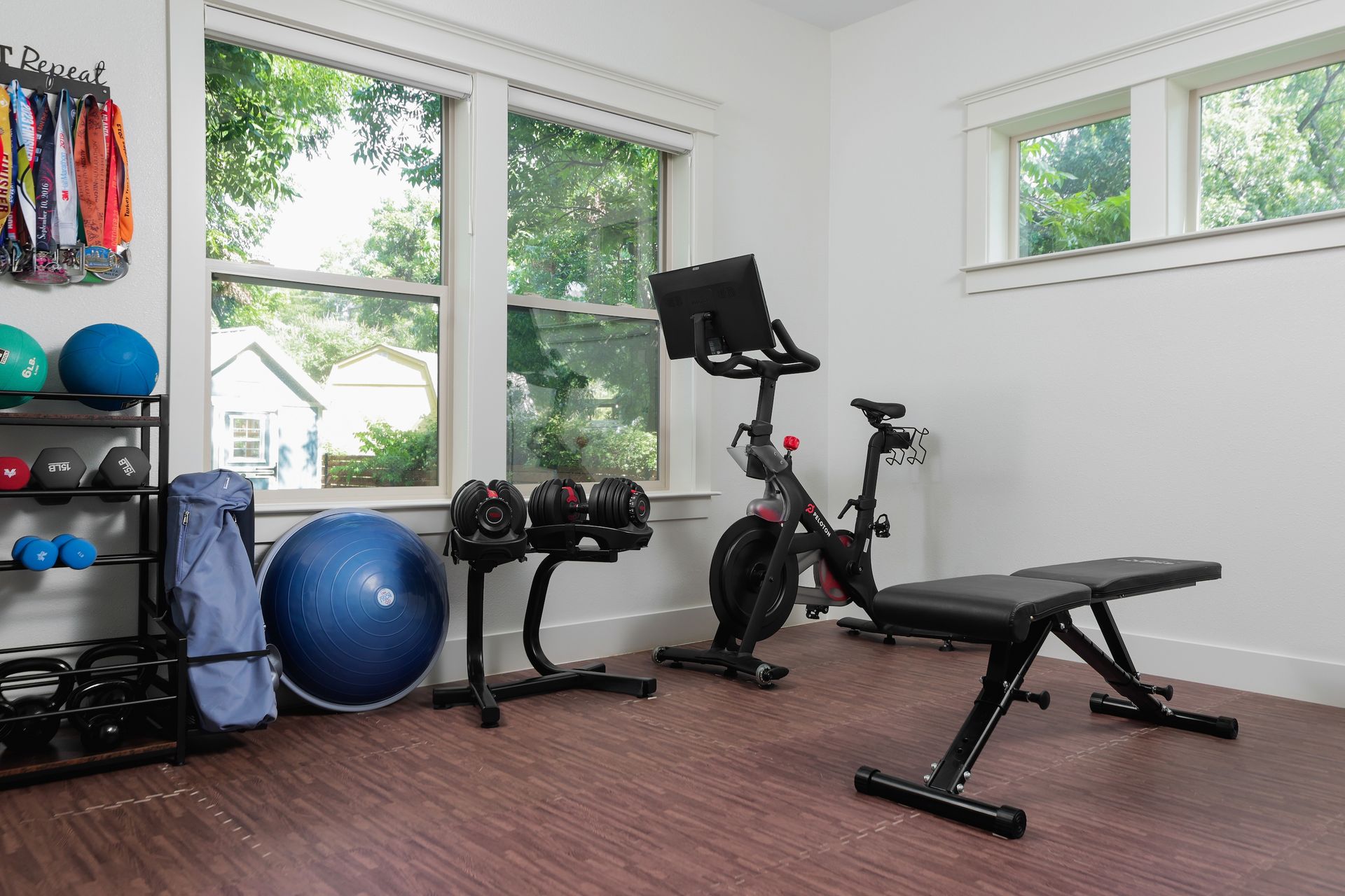 A home gym with a bike , bench , dumbbells , and a pilates ball.