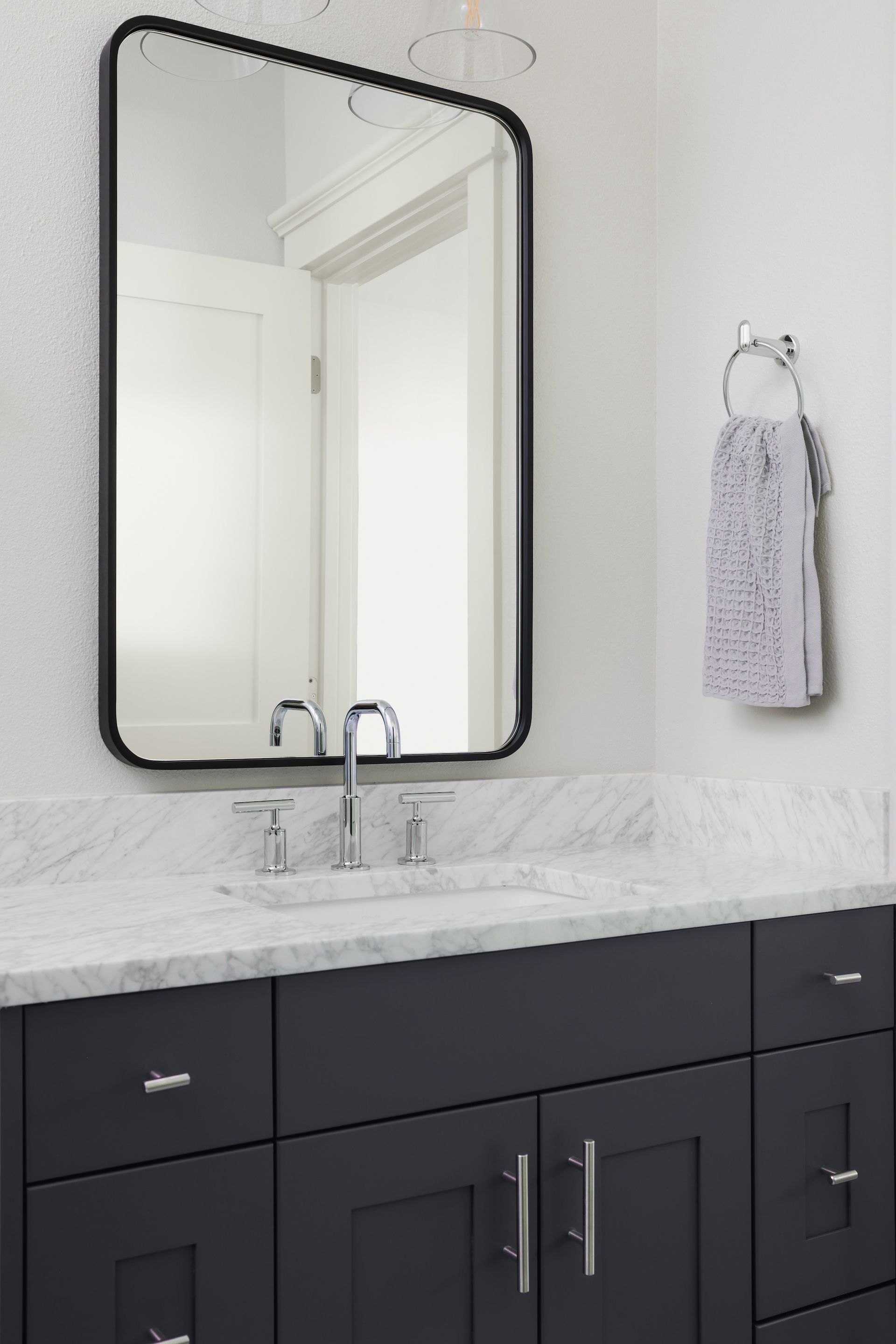 A bathroom with a sink , mirror and towel hanging on the wall.
