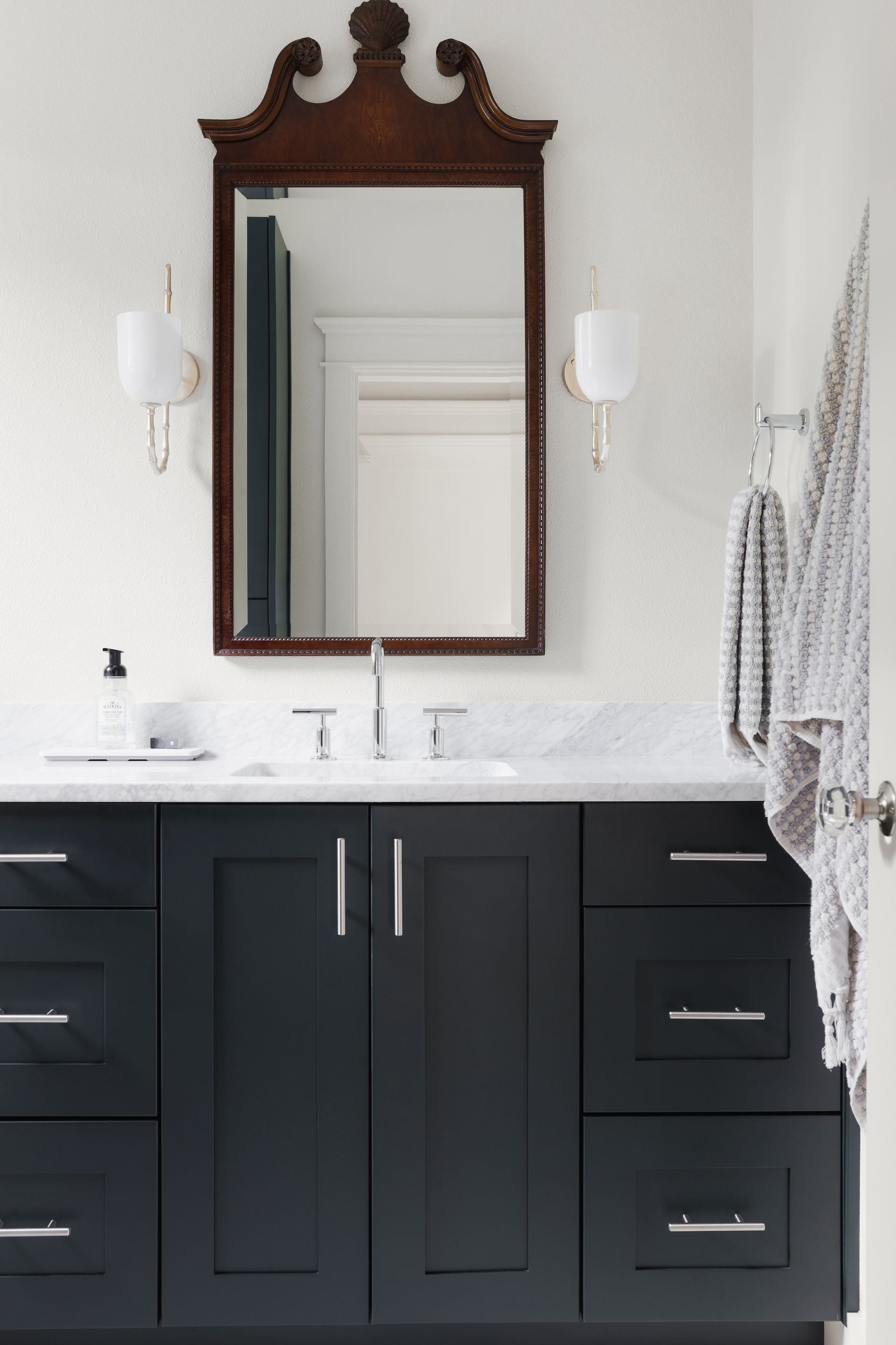 A bathroom with black cabinets and a large mirror