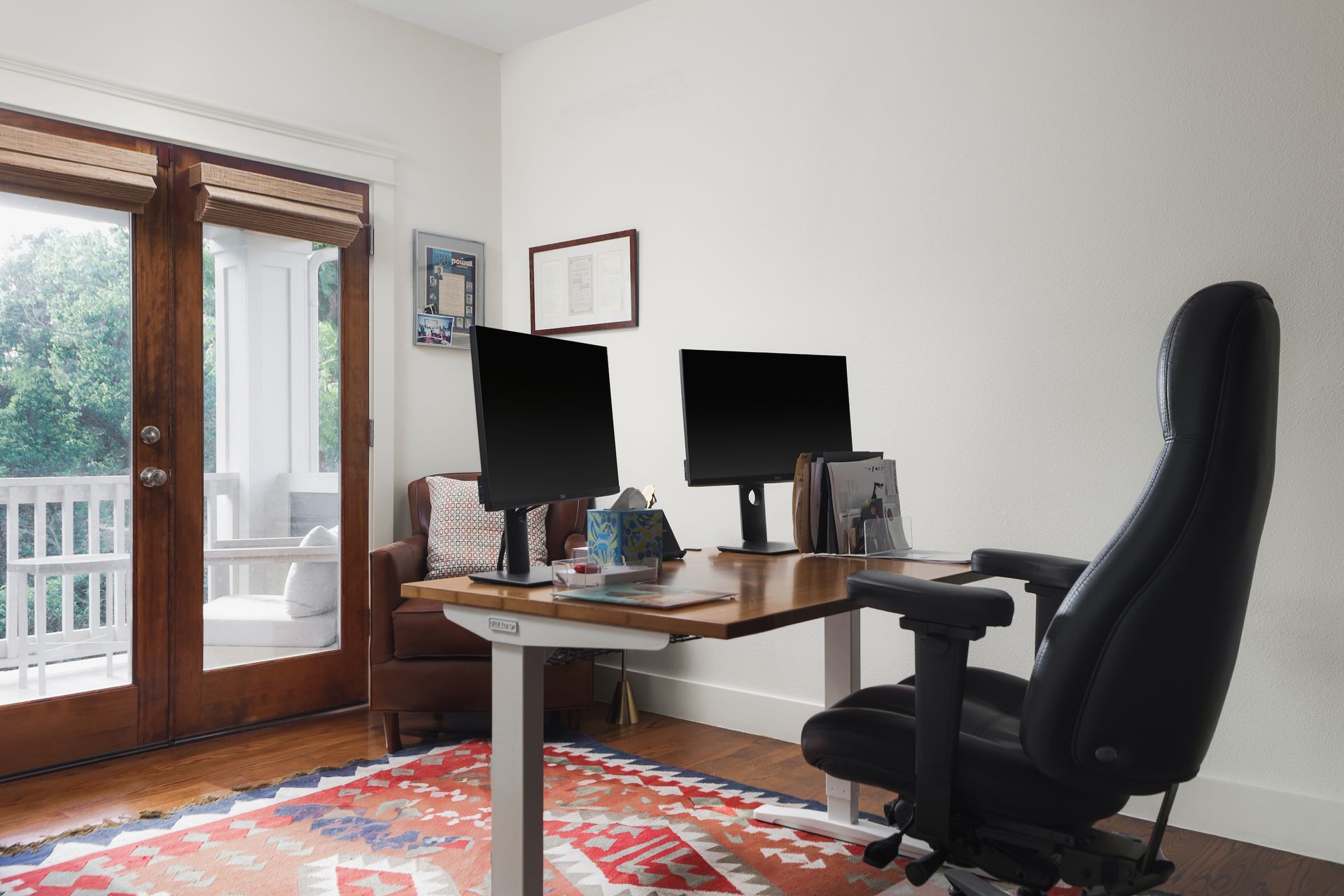 A home office with two computer monitors and a chair.