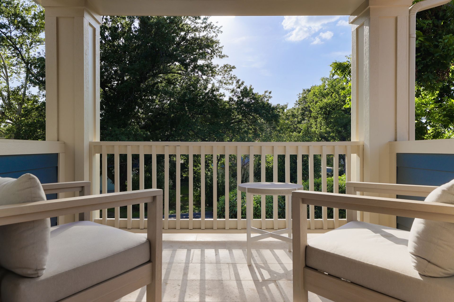 A balcony with two chairs and a table with a view of trees.